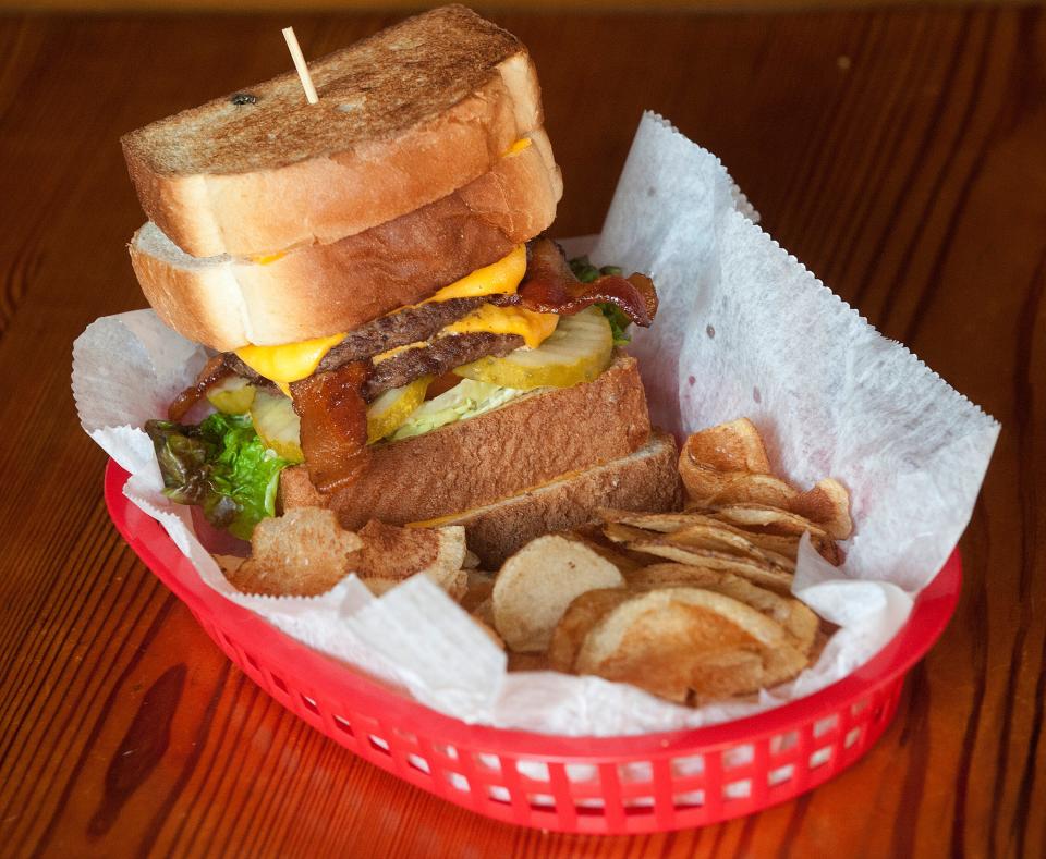 The Silver Dollar Bar and Restaurant's ultimate burger is topped with bacon, lettuce and tomato, pickles, American cheese, and served between two grilled cheese sandwiches. The dish is often accompanied by an order of French fries or home-made potato chips (seen here.)September 04, 2018