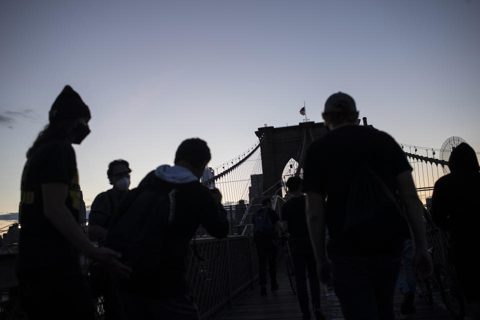 Demonstrators are seen in silhouette during a march across the Brooklyn Bridge as part of a solidarity rally calling for justice over the death of George Floyd Monday, June 1, 2020, in the Brooklyn borough of New York. Floyd died after being restrained by Minneapolis police officers on May 25. (AP Photo/Wong Maye-E)