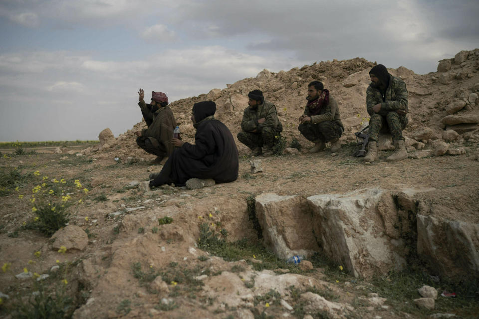 Combatientes de las Fuerzas Democráticas Sirias respaldadas por Estados Unidos están sentados en una colina en el desierto afuera de la aldea de Baghouz, Siria, el jueves 14 de febrero de 2019. (AP Foto/Felipe Dana)