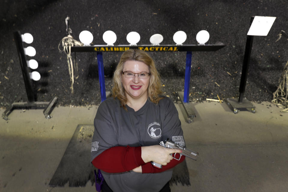 In this Wednesday, Feb. 5, 2020, photo, Kat Ellsworth of Chicago, poses for a portrait with one of the seven guns she owns at the Caliber Tactical Gun Range in Waukegan, Ill. Looking at the upcoming election, she's torn as a self-described liberal and registered Democrat. "I'm still probably going to follow the 'vote blue no matter who' but I don't know that I'll be happy about it," she said. (AP Photo/Charles Rex Arbogast)