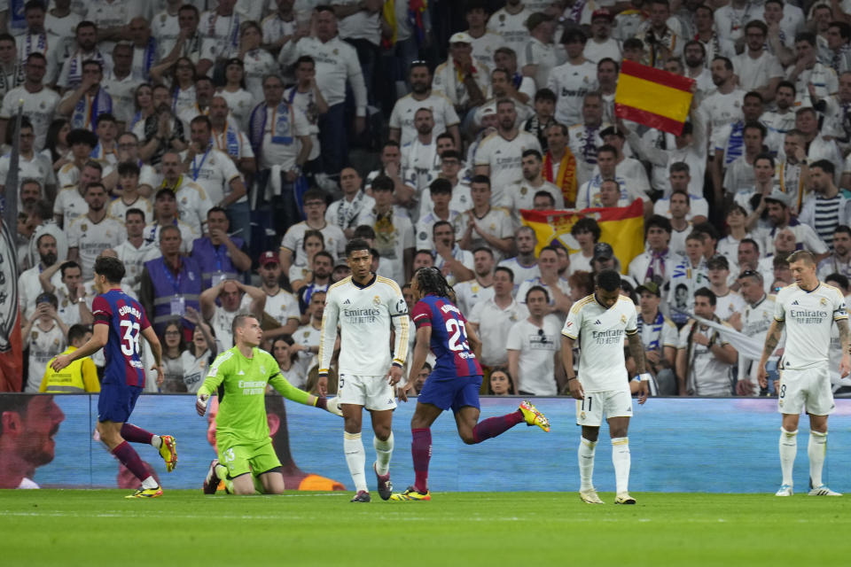 Real Madrid's goalkeeper Andriy Lunin, second left, reacts as Barcelona players celebrate after their teammate Andreas Christensen scores his side's opening goal during the Spanish La Liga soccer match between Real Madrid and Barcelona at the Santiago Bernabeu stadium in Madrid, Spain, Sunday, April 21, 2024. (AP Photo/Manu Fernandez)