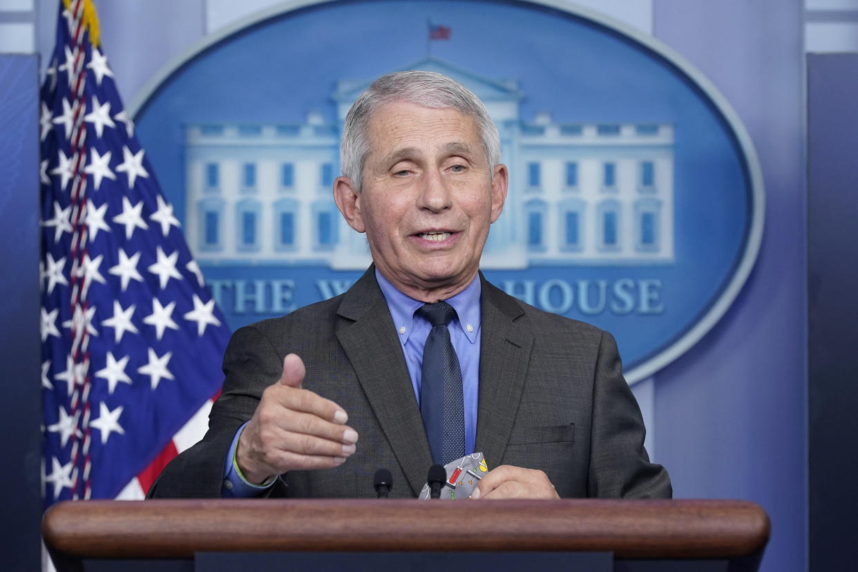 Dr. Anthony Fauci at the microphone in front of a White House plaque. 