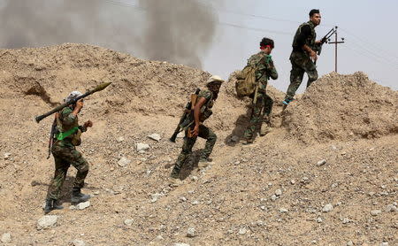 Iraq's Shi'ite paramilitaries walk with their weapons in Nibai May 26, 2015. REUTERS/Stringer