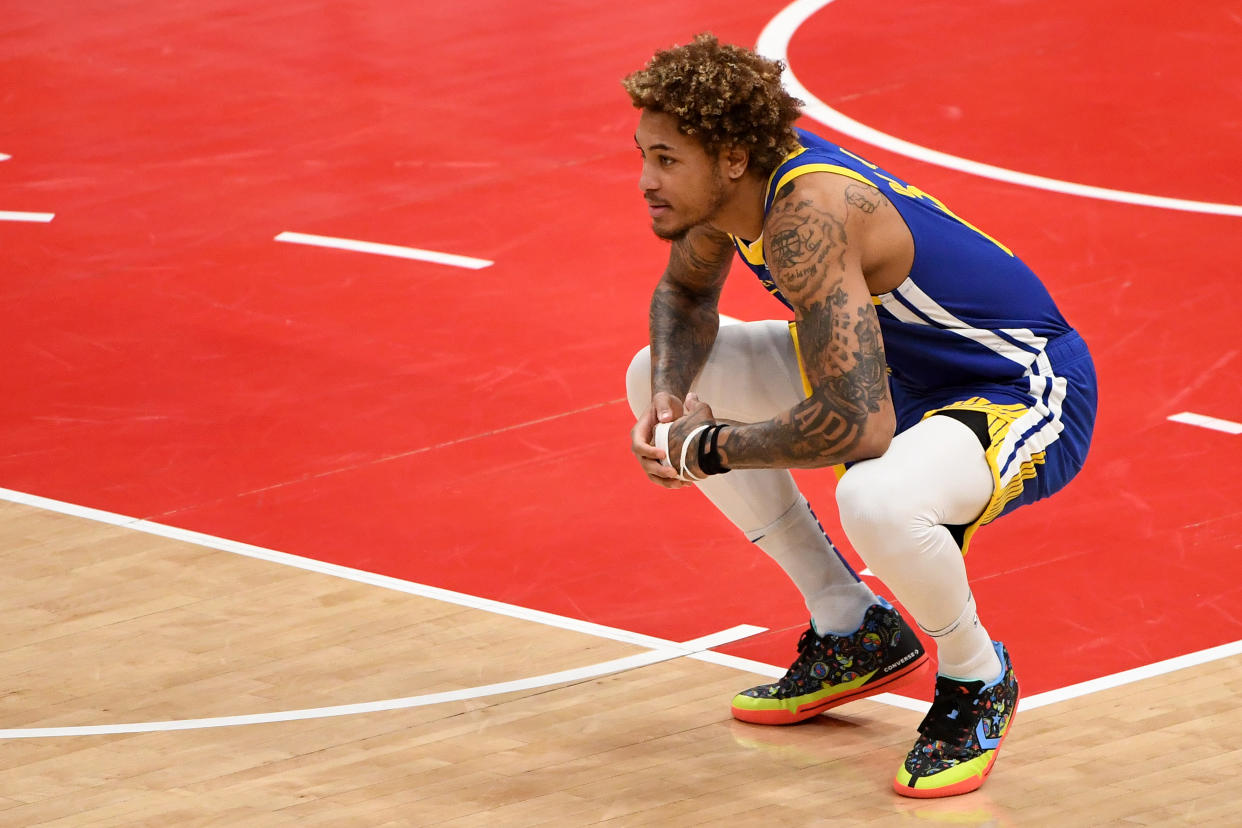 Kelly Oubre Jr. squats down and looks on during a game.