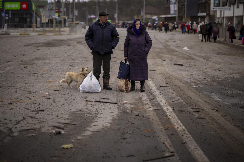 A couple stand on the road waiting for transportation after crossing the Irpin river in the outskirts of Kyiv, Ukraine, Saturday, March 5, 2022. (AP Photo/Emilio Morenatti)