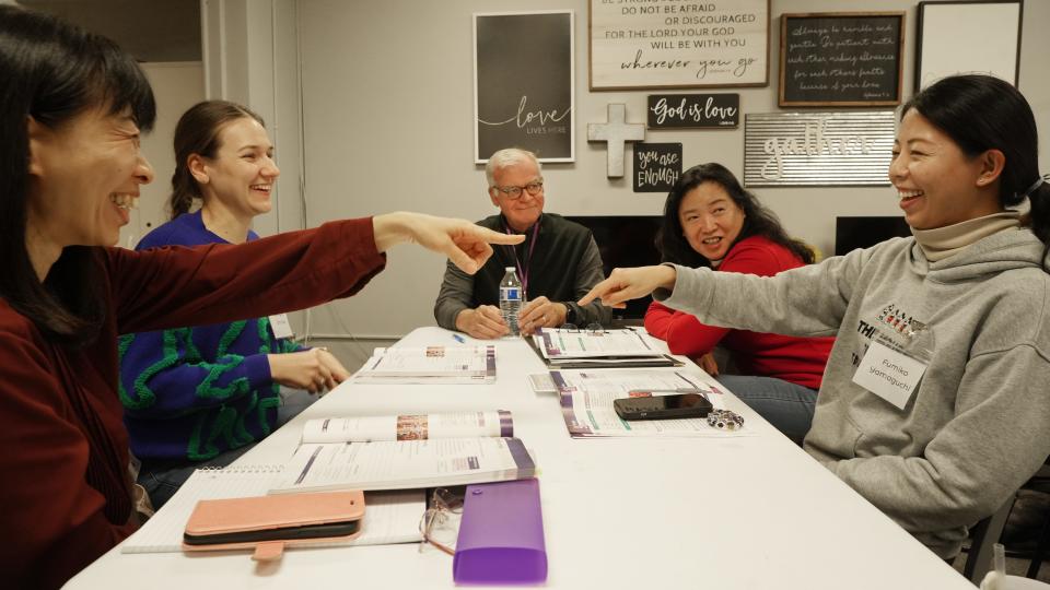 Immigrants joke during a three-generation English as a Second Language program run by Festa, a local nonprofit group. From left is Kyoko Kojima from Japan, Kateryna Smolka from Ukraine, volunteer Ulrik Nygaard, Sandy Pan from China, and Fumiko Yamaguchi from Japan. While parents and grandparents learn English, their children receive supervised playtime, homework help and dinner.