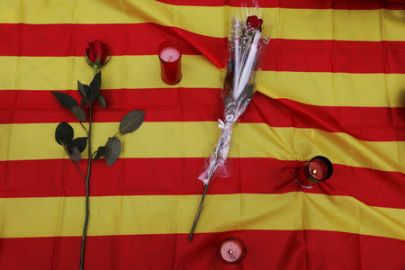 Flowers and candles lay on a Catalan flag at an impromptu memorial where a van crashed into pedestrians at Las Ramblas in Barcelona, Spain, August 20, 2017. REUTERS/Susana Vera