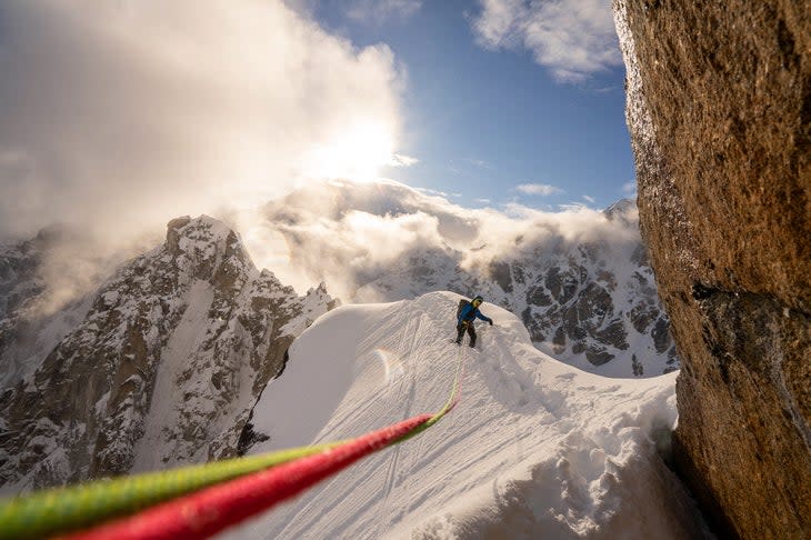 Alpinist traverse snowy ridge in Alaska.