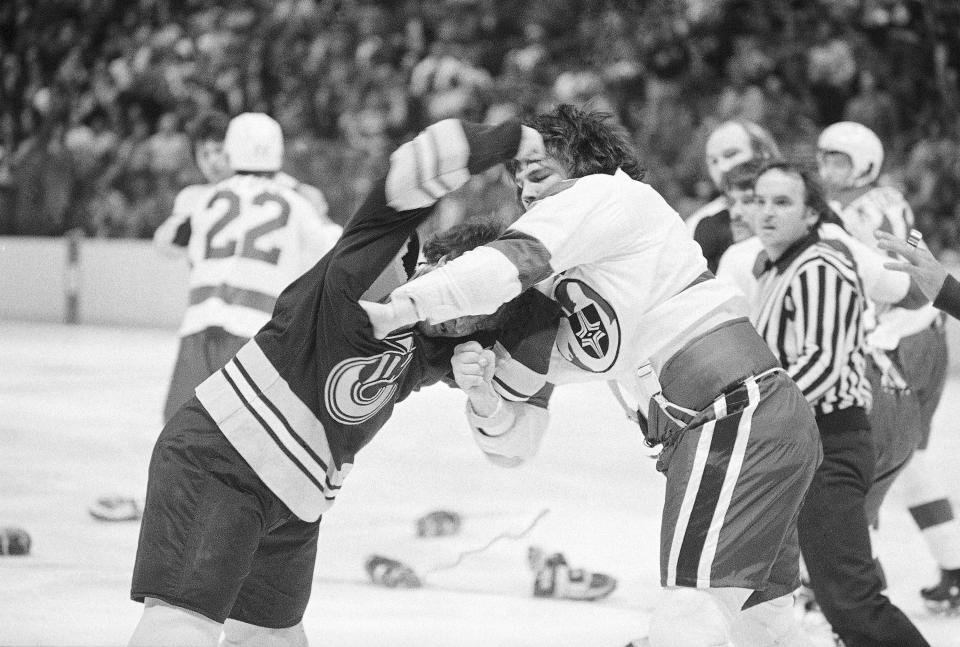 FILE - Cleveland Crusaders' Bryan Maxwell, right, takes a blow to the head from Cincinnati Stingers' Bruce Abbey in the first period of a World Hockey Association game in Richfield, Ohio, Oct. 11, 1975. The American Basketball Association and World Hockey Association have been gone for decades, but their brash challenges to the set-in-their-ways NBA and NHL left a mark that is still recognizable today. (AP Photo/G. Paul Burnett, File)
