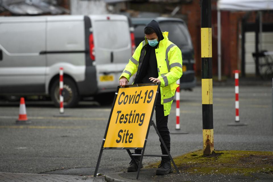 A NHS 'test and trace' worker moves a sign  at a drive through/walk up Covid-19 testing facility in Moston, geater Manchester on February 19, 2021, as a handful of cases of a Covid-19 'variant of concern' has surfaced in the area. (Photo by Oli SCARFF / AFP) (Photo by OLI SCARFF/AFP via Getty Images)