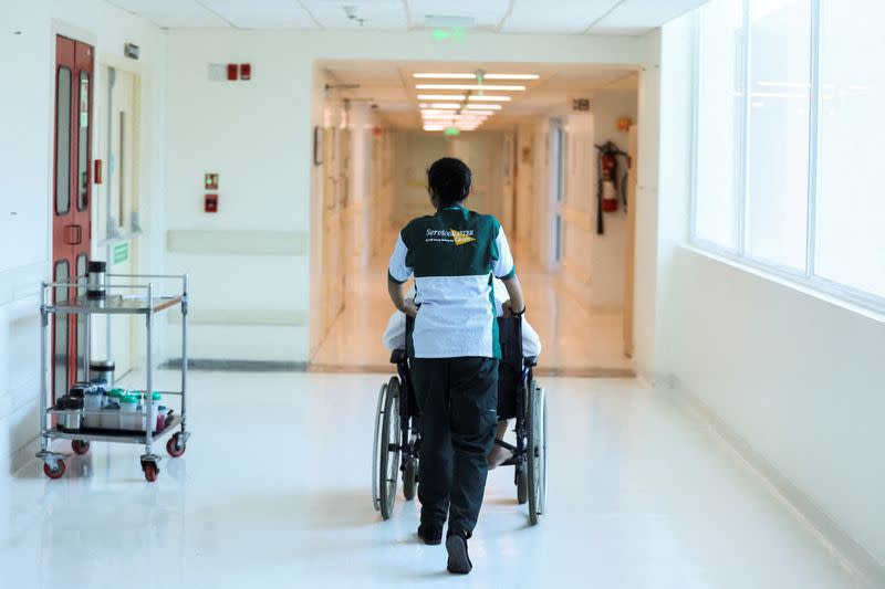 FILE PHOTO: An attendant wheels a patient through a hospital in New Delhi