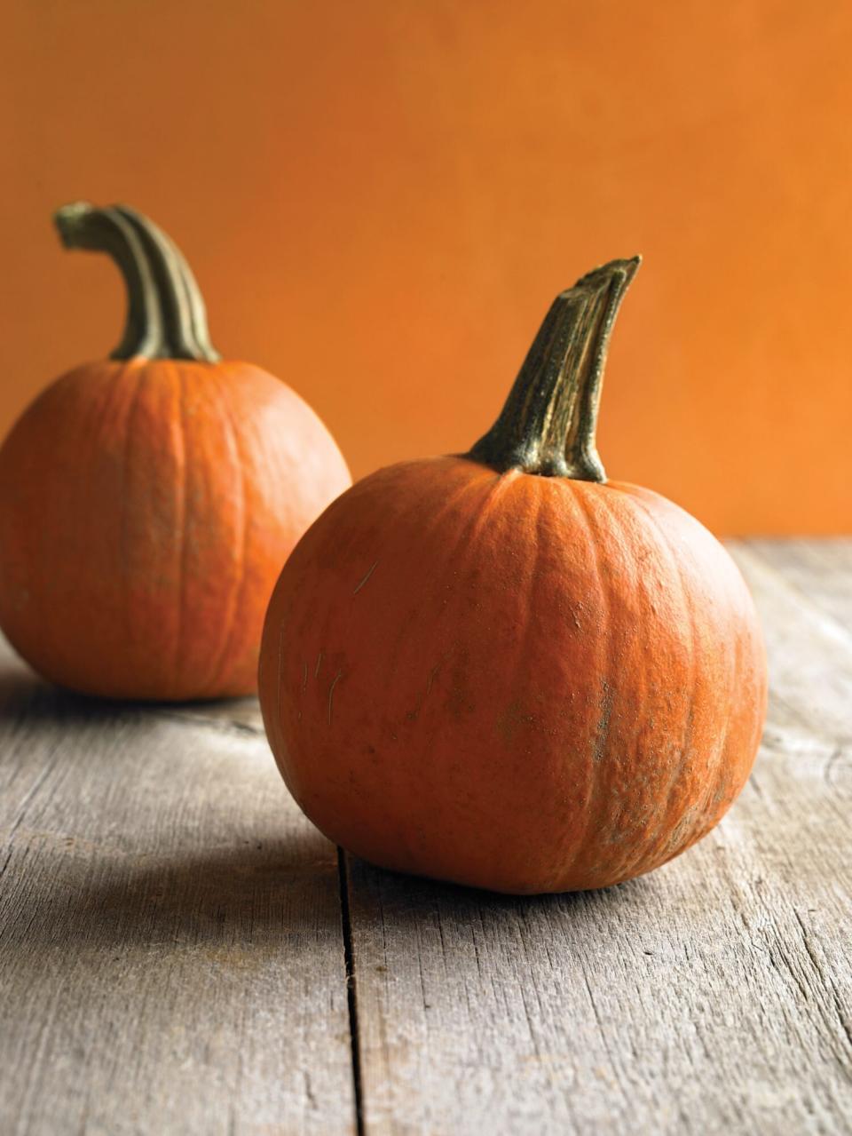 whole sugar pumpkins on wood surface