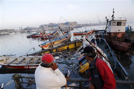 Fishermen look at sunken boats, after a series of aftershocks, in the northern port of Iquique April 3, 2014. REUTERS/Ivan Alvarado