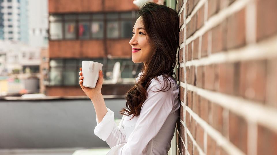 Young business woman having a break drinking an hot coffee on the rooftop of his office building in downtown Seoul, South Korea.