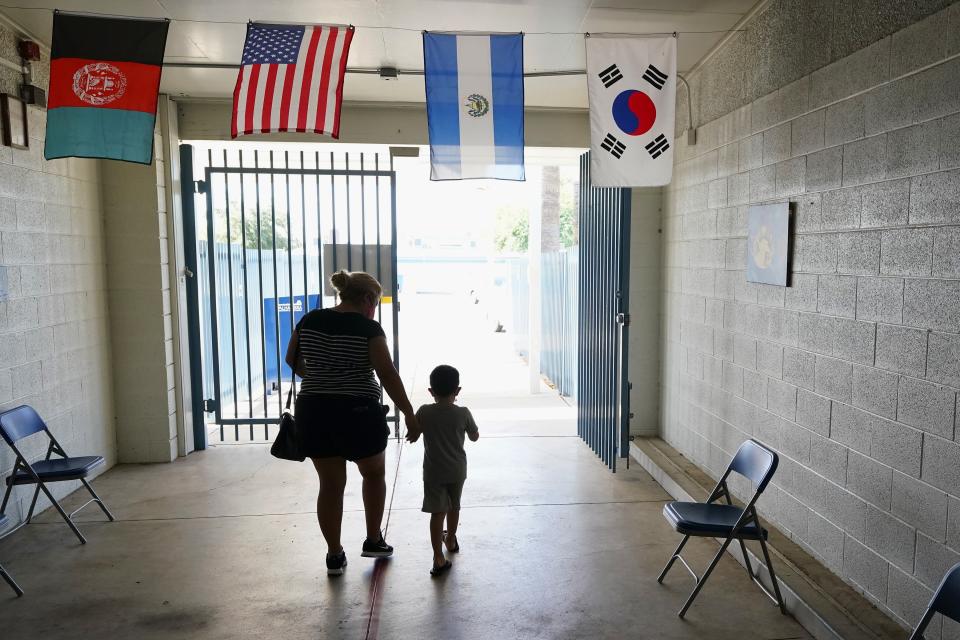 Fernando Barron Escalante, right, walks with Noelia Leyva, a family friend who cares for the 5-year-old while his mother works, exits the Valencia Newcomer School after getting some help setting up his new iPad for remote learning due to the coronavirus Tuesday, Sept. 2, 2020, in Phoenix. (AP Photo/Ross D. Franklin)