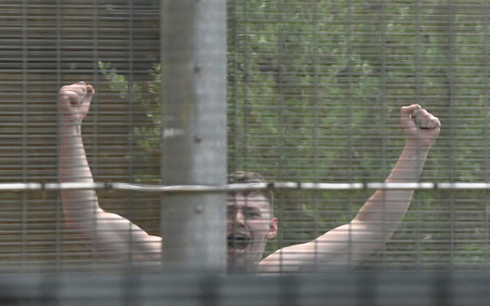 A detainee inside the Brook House Immigration Removal Centre, as demonstrators protest outside - Toby Melville/Reuters