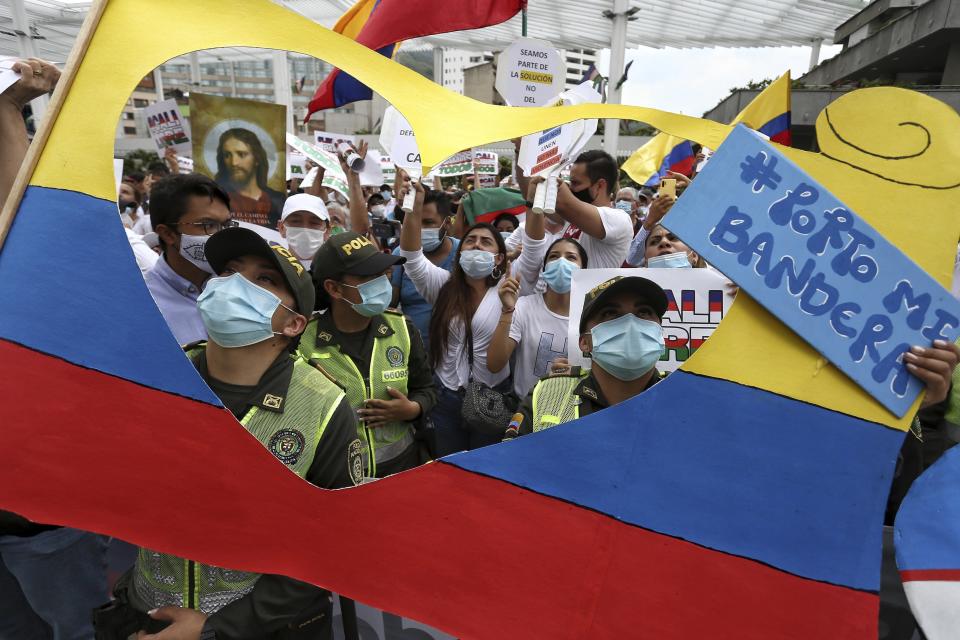 Police and civilians attend a silent march to support the unblocking of the city's main entrance and exit roads that have been blocked by anti-government protests in Cali, Colombia, Tuesday, May 25, 2021. Colombians have taken to the streets for weeks across the country after the government proposed tax increases on public services, fuel, wages, and pensions. (AP Photo/Andres Gonzalez)