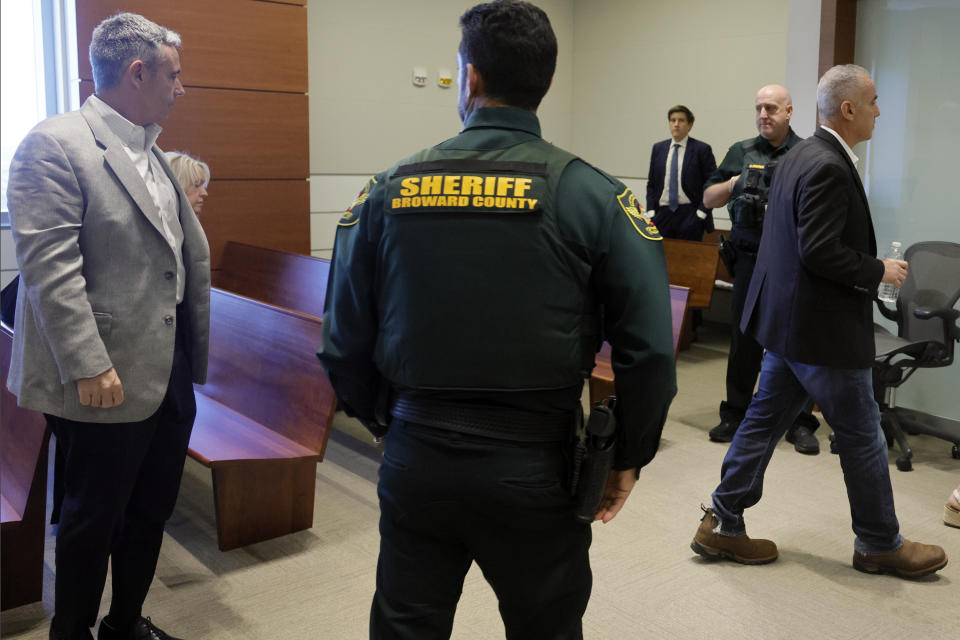 A Broward County sheriff's deputy stands by as Andrew Pollack, right, and Tom Hoyer, left, exit the courtroom for a lunch break during a hearing at the Broward County Courthouse in Fort Lauderdale, Fla., Monday, Dec. 18, 2023. Hoyer's son, Luke, and Pollack's daughter, Meadow, were killed in the 2018 shootings at Marjory Stoneman Douglas High School. (Amy Beth Bennett/South Florida Sun-Sentinel via AP, Pool)