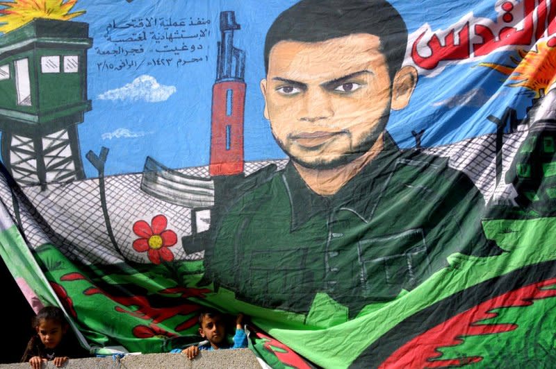 Palestinian children watch masked members of the Islamic Jihad Movement march during a rally October 31, 2003 in Beit Lahiya in north Gaza. About 3,000 supporters held a gathering marking the eighth anniversary of the assassination of the Islamic Jihad Movement founder Fathi Shaqaqi in Malta on October 26, 1995. File Photo by Ismael Mohamad/UPI