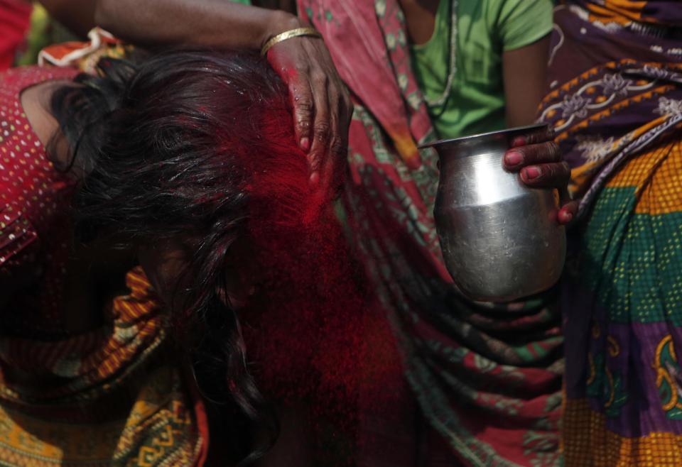 In this Wednesday, Nov. 23, 2016 photo, family members rinse out the red tikka powder, which is only allowed for married women, from the forehead of Saro Kumari Mandal, 26, after the death of her husband Balkisun Mandal Khatwe, 26, at Belhi village, in Saptari district, Nepal. Balkisun died in his sleep in Qatar, where he was working for Habtoor Leighton Group, loading trucks to build new highways. The number of Nepali workers going abroad has more than doubled since the country began promoting foreign labor in recent years: from about 220,000 in 2008 to about 500,000 in 2015. Yet the number of deaths among those workers has risen much faster in the same period. In total, over 5,000 workers from this small country have died working abroad since 2008, more than the number of U.S. troops killed in the Iraq War. (AP Photo/Niranjan Shrestha)