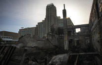 A former Sears building, now known as the Midtown Market place, stands behind buildings destroyed in a fire from riots Sunday May 31, 2020, in Minneapolis. Outrage following the death of George Floyd, who died after being restrained by Minneapolis police officers on May 25, has led to the burning of businesses along the Lake Street corridor where immigrants have found success. (AP Photo/Bebeto Matthews)