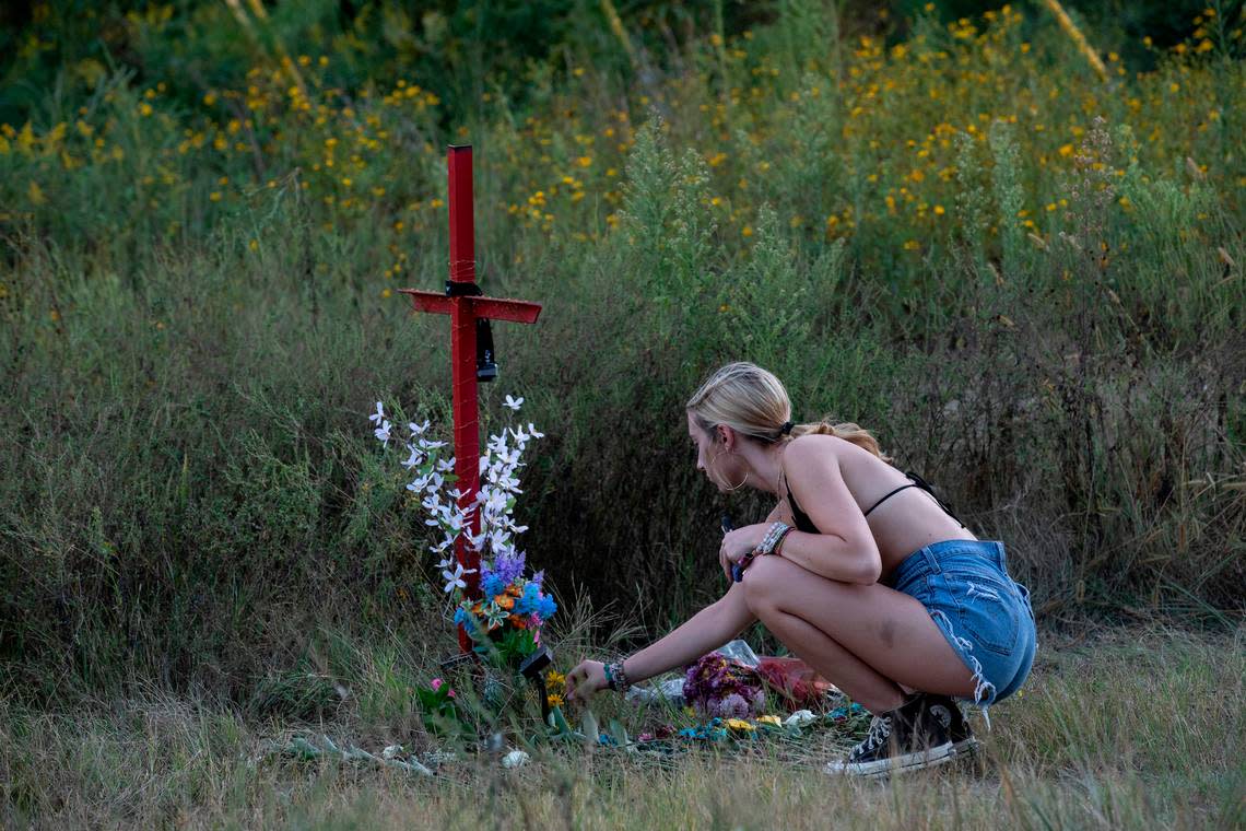 Emmalee Murphy lays flowers at the base of a memorial for Lyric Woods, 14, and Devin Clark, 18, in Orange County on Tuesday, Sept. 20, 2022. The Orange County Sheriff’s Office said Monday the two young people found shot and killed Sunday in western Orange County are Woods and Clark.