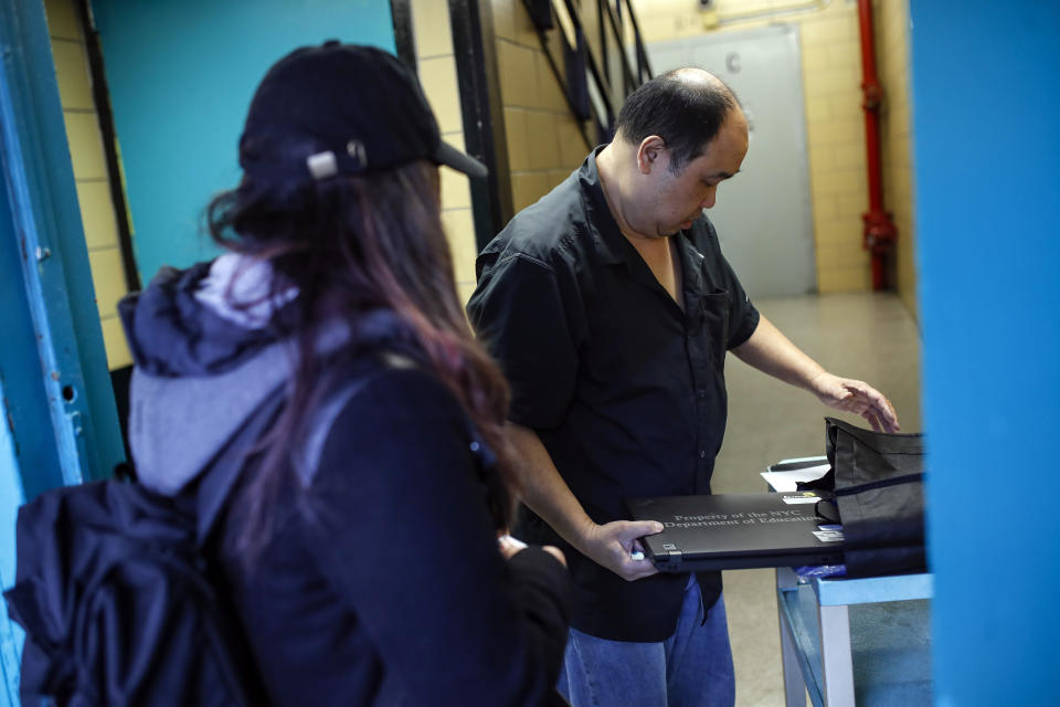 Anna Louisa, 18, left, receives her school laptop for home study at the Lower East Side Preparatory School, Thursday, March 19, 2020, in New York, as coronavirus restrictions shuttered classrooms throughout the city. New York Gov. Andrew Cuomo tightened work-from-home rules as confirmed cases continued to climb in New York, an expected jump as testing becomes more widespread. (AP Photo/John Minchillo)