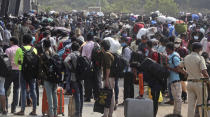 People wearing masks as a precaution against the coronavirus stand in queues to board trains at Lokmanya Tilak Terminus in Mumbai, India, Wednesday, April 14, 2021. India is experiencing its worst pandemic surge, with average daily infections exceeding 143,000 over the past week. (AP Photo/Rafiq Maqbool)