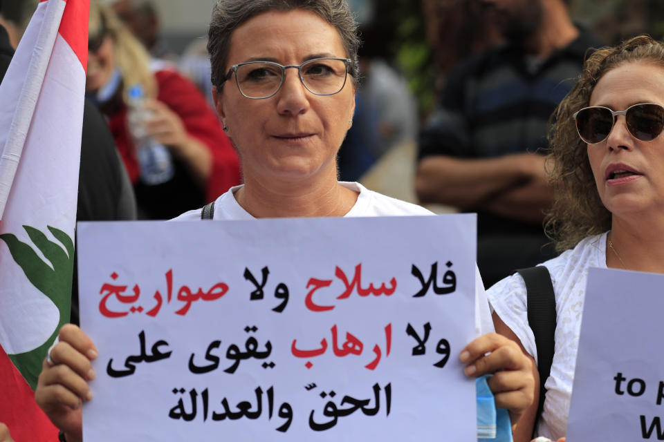 A supporter of Lebanese opposition groups holds an Arabic placard against Hezbollah that reads: "No weapons, rockets or terrorist can be stronger than right and justice," during a sit-in outside the justice palace to show their solidarity with Judge Tarek Bitar, who is investigating last year's deadly seaport blast, in Beirut, Lebanon, Tuesday, Oct. 19, 2021. Hezbollah leader Hassan Nasrallah’s boast that he has 100,000 armed fighters that can be deployed against internal rivals came as a surprise to many Lebanese, not least because it was addressed to a domestic audience rather than the group’s archenemy Israel. (AP Photo/Hussein Malla)