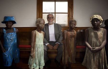 John Cummings sits for a portrait amongst terra-cotta statues of slave children inside of a church at the Whitney Plantation in Wallace, Louisiana on January 13, 2015. REUTERS/Edmund Fountain