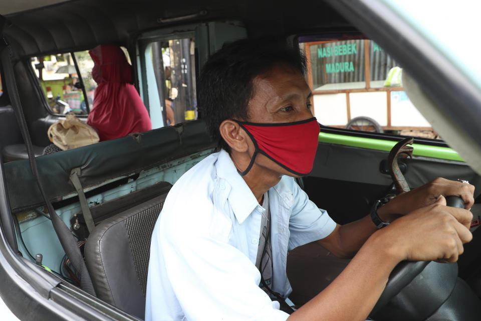 A minivan driver waits for passengers in Jakarta, Indonesia, Friday, April 10, 2020. Authorities began stricter measures to halt the new coronavirus' spread in Indonesia's capital Friday, with its normally congested streets empty after death toll spiked in the past week. (AP Photo/Achmad Ibrahim)