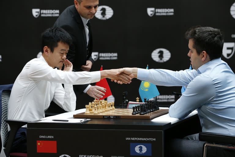 Ding Liren de China, izquierda, e Ian Nepomniachtchi de Rusia se dan la mano antes de definir el Campeonato Mundial de Ajedrez de la FIDE en Astana, Kazajstán