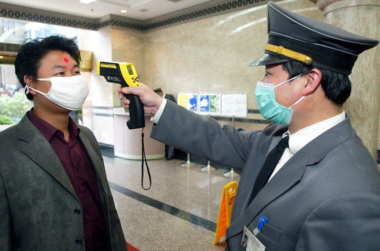 A security man checks the temperature of a man entering an office block in Shanghai on May 12, 2003. SARS infected about 8,000 people around the world, claiming most of its victims in Hong Kong, Taiwan, mainland China, Canada and Singapore