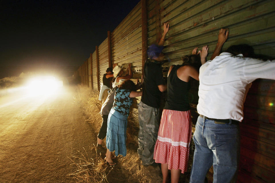 Migrant activists lean against the border fence to pay homage to undocumented&nbsp;immigrants who died crossing over.