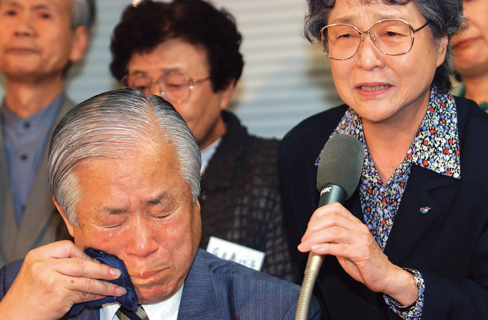 Shigeru Yokota, bottom left, wipes tears as he and his wife Sakie, right, speak during a press conference in Tokyo in September, 2002 after they were informed that their daughter Megumi, abducted to North Korea in the 1970s, had died. Shigeru Yokota died of natural causes before he was able to meet his daughter again, his group said Friday, June 5, 2020. He was 87. (Kyodo News via AP)