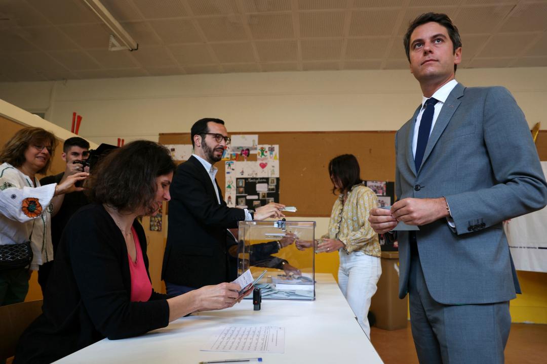 French Prime Minister Gabriel Attal, right, waits to vote for the second round of the legislative elections, Sunday, July 7, 2024 in Vanves, outside Paris. Voting has begun in mainland France on Sunday in pivotal runoff elections that could hand a historic victory to Marine Le Pen's far-right National Rally and its inward-looking, anti-immigrant vision — or produce a hung parliament and years of political deadlock. (Alain Jocard, Pool via AP)