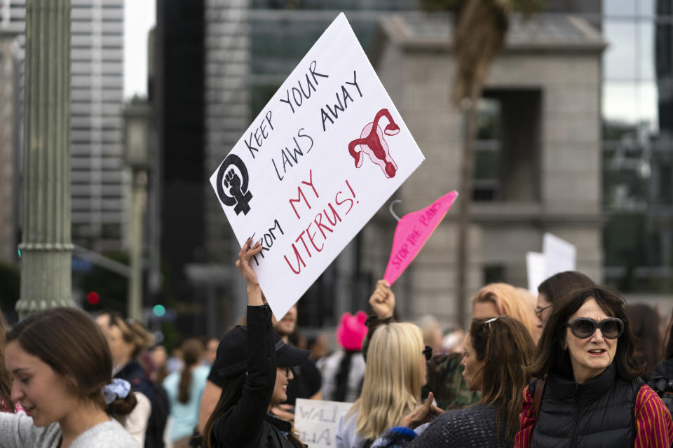 An activist seen holding a placard that says 'keep your laws away from my uterus' during the protest