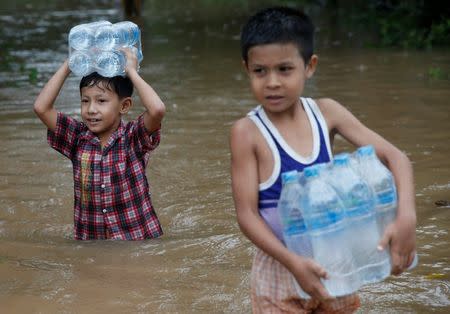 Boys carry water bottles distributed by an aid organization during the flood in Kyaikto township, Mon state, Myanmar July 22, 2017. REUTERS/Soe Zeya Tun