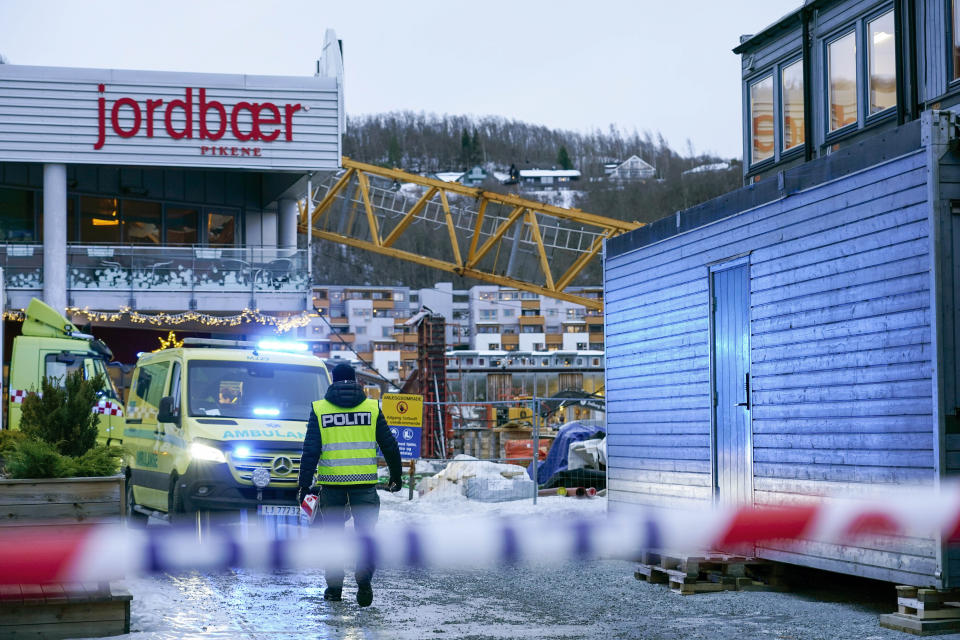 Emergency services at the scene after a construction crane fell over Melhustorget shopping mall, in Melhus, Norway, Friday, Jan. 6, 2023. Strong winds likely have knocked over a construction crane which crashed over a shopping mall in central Norway. Police said one person was unaccounted for and at least one person was slightly injured. (Gorm Kallestad /NTB Scanpix via AP)