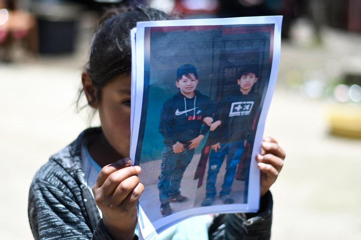 A girl holds a portrait of Melvin Guachiac (L) and Wilmer Tulul -killed inside a tractor-trailer in Texas after crossing from Mexico- in Tzucubal village, Nahuala, Guatemala, on June 30, 2022. - Melvin and his cousin Wilmer, both 13, were among the 51 migrants who died after they were abandoned in a suffocatingly hot tractor-trailer truck in the US state of Texas. (Photo by Johan ORDONEZ / AFP) (Photo by JOHAN ORDONEZ/AFP via Getty Images)