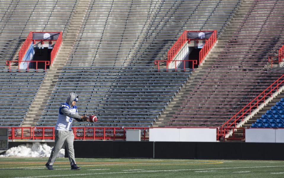 Football player stands in empty stadium