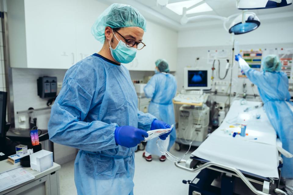 Ein Notfallmediziner legt eine FFP2-Maske an im Schockraum der Notaufnahme im Krankenhaus. (Symbolbild)
