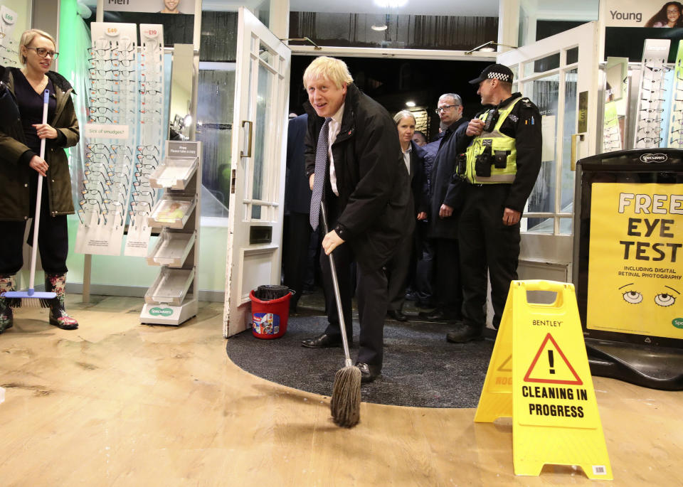 Britain's Prime Minister Boris Johnson visits an optician shop after flooding, in Matlock, north England, Friday Nov. 8, 2019. A woman died after being swept away by surging waters as torrential rain drenched parts of north and central England, swelling rivers, forcing evacuations and disrupting travel for a second day Friday. (Danny Lawson/PA via AP)