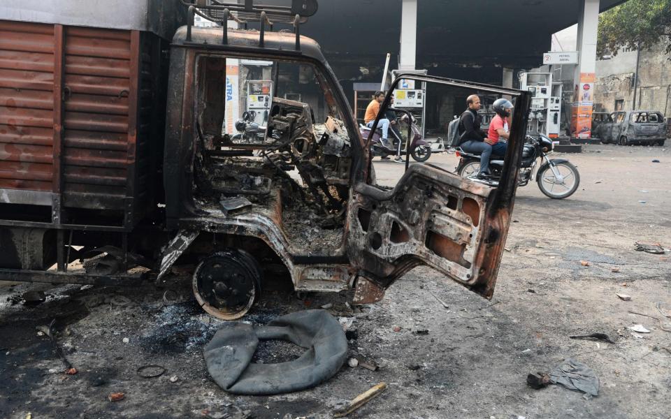 Motorists ride past a burnt-out vehicle following the clashes  - AFP