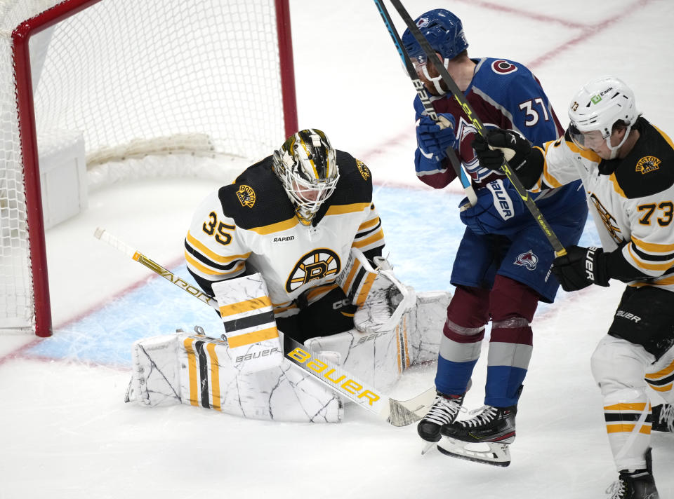 Boston Bruins goaltender Linus Ullmark, left, makes a stop of a redirtected shot off the stick of Colorado Avalanche left wing J.T. Compher, center, as Boston defenseman Charlie McAvoy defends during the first period of an NHL hockey game Wednesday, Dec. 7, 2022, in Denver. (AP Photo/David Zalubowski)