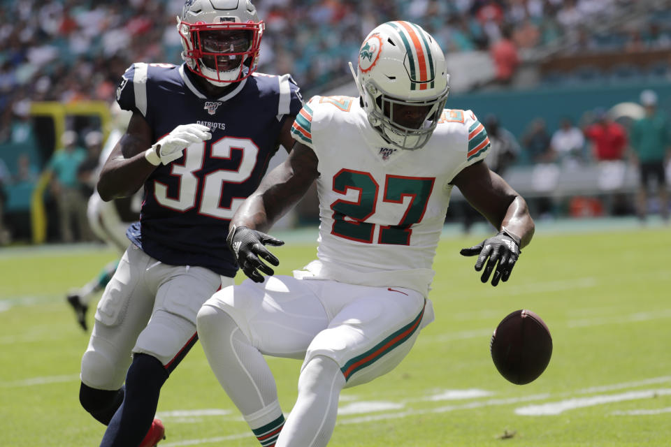 Miami Dolphins running back Kalen Ballage (27) drops a pass under pressure from New England Patriots free safety Devin McCourty (32), during the first half at an NFL football game, Sunday, Sept. 15, 2019, in Miami Gardens, Fla. (AP Photo/Lynne Sladky)