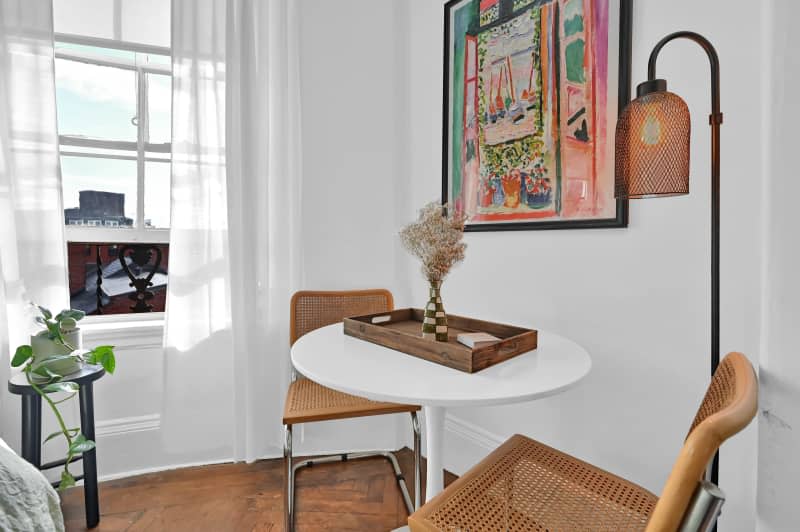 Two whicker chairs with surrounding a circular white table.