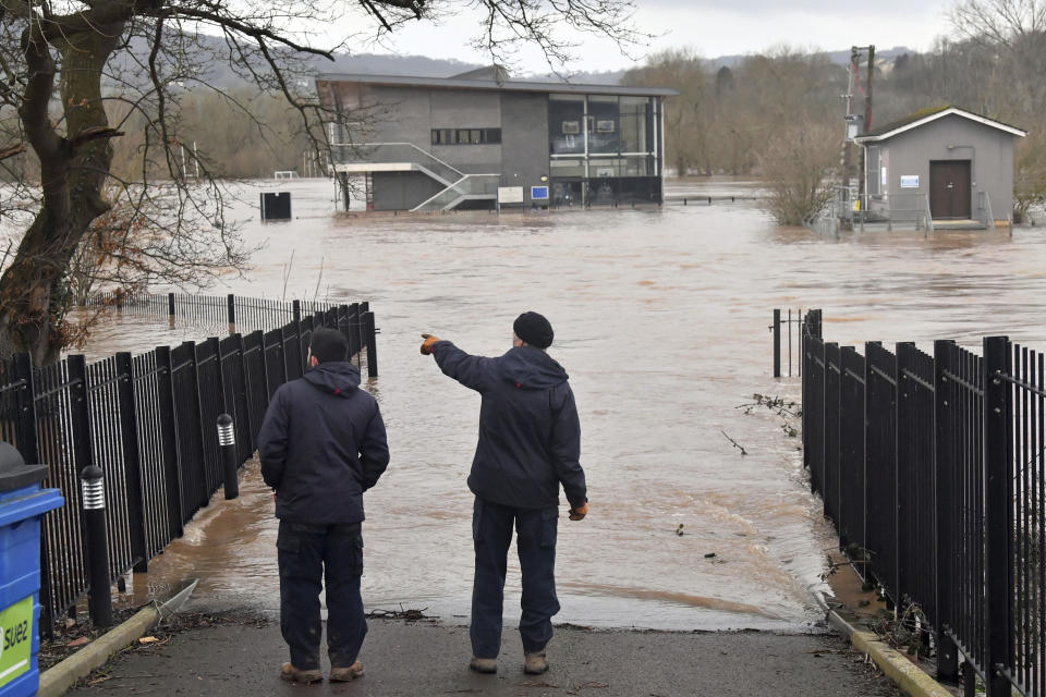 Two men look at the flooded sports pavilion at Monmouth School, Wales, Tuesday Feb. 18, 2020. Britain's Environment Agency issued severe flood warnings Monday, advising of life-threatening danger after Storm Dennis dumped weeks' worth of rain in some places. (Ben Birchall/PA via AP)