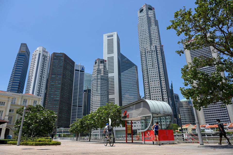 People pass by along the river quay at the financial business district in Singapore on April 20, 2021. (Photo by Roslan RAHMAN / AFP) (Photo by ROSLAN RAHMAN/AFP via Getty Images)