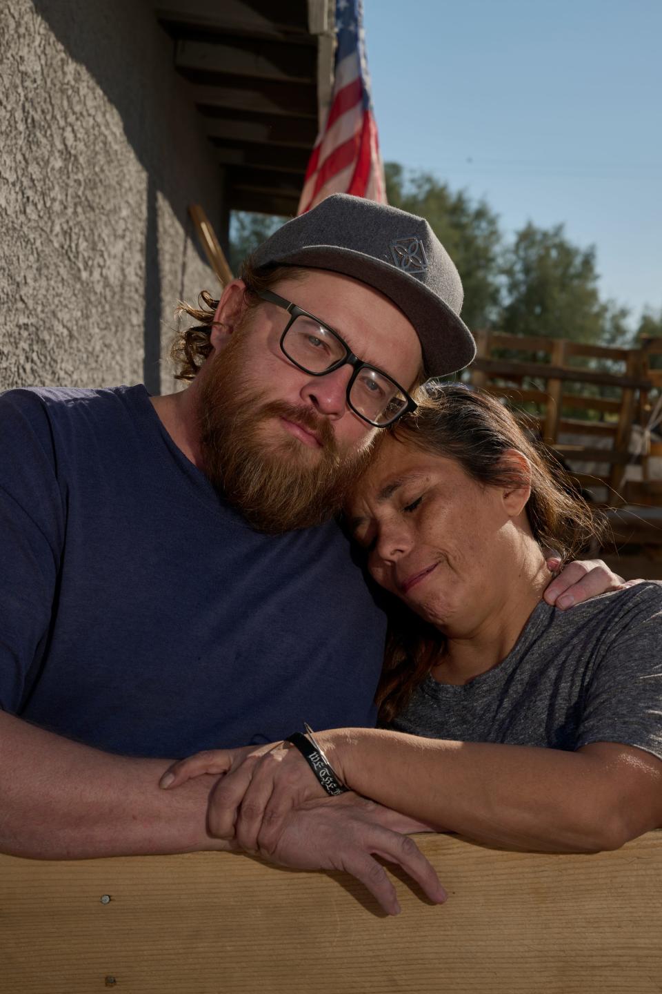 A couple posing next to each other under a roof and an American flag.